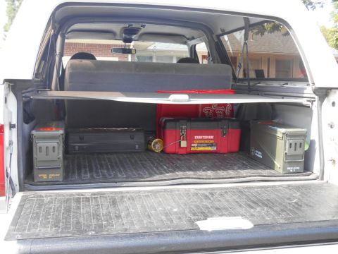 1994 Ford Bronco - The cargo area of a white SUV contains various tools and containers, with visible interior paneling.