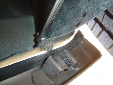 1996 Ford Bronco - A wrench is used to remove a clip from a vehicle's fender liner, revealing a part of the tire tread.