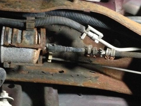 1996 Ford Bronco - Close-up view of the vehicle's undercarriage, revealing various mechanical components and signs of rust.