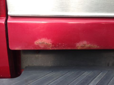 1995 Ford Bronco - Rust is visible on the lower section of a red vehicle's tailgate.