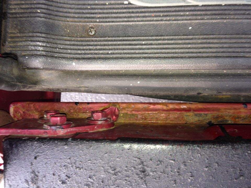 rusted metal bracket with bolts, part of a vehicle's undercarriage