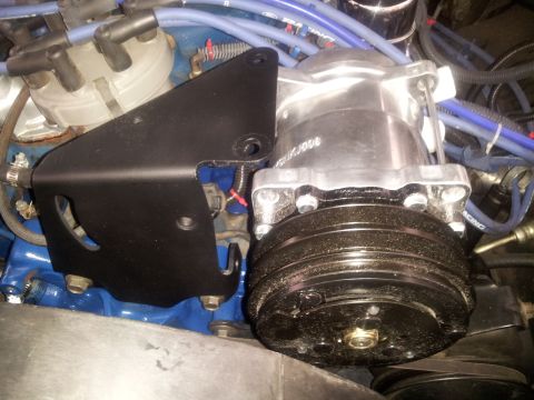 1976 Ford Ranchero - Close-up view of an engine's air conditioning compressor and mounting bracket, with visible blue spark plug wires.