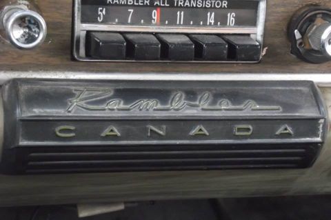 1964 AMC Javelin - Close-up of a car's interior showing a Rambler Canada emblem and an AM transistor radio.