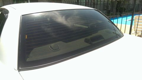 2000 Mercury Grand Marquis - Rear view of a white sedan showing the back window and trunk lid, with a pool in the background.