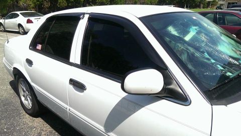 2000 Mercury Grand Marquis - A white 2000 Mercury Grand Marquis sedan is parked outdoors, showing its side profile with tinted windows.