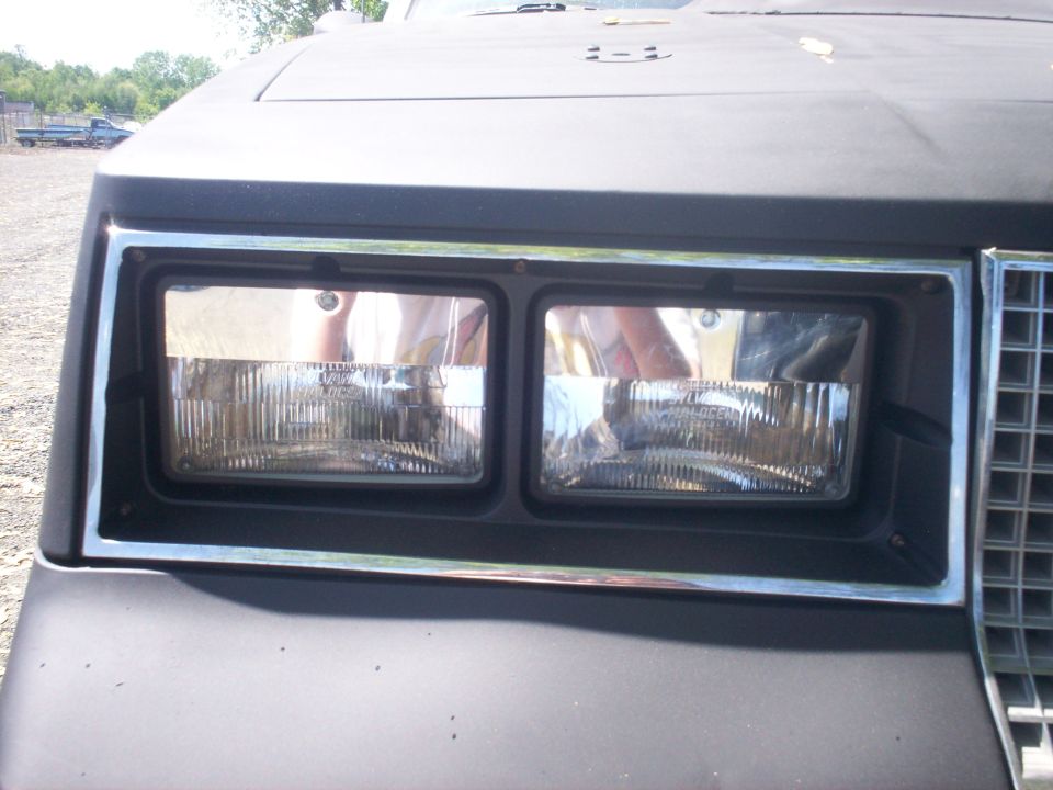 Black car's dual rectangular headlights with chrome trim, front view