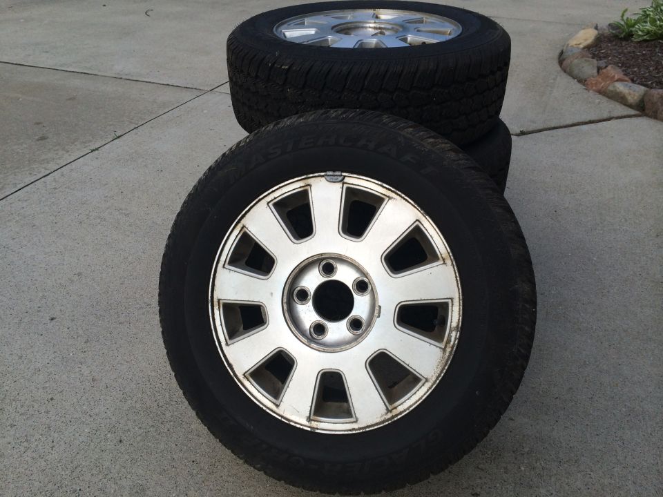 stack of four tires with silver rims on concrete
