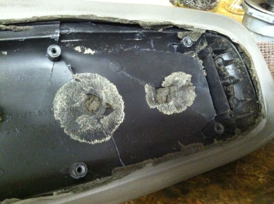 Interior armrest part with cracked mounting points and visible text