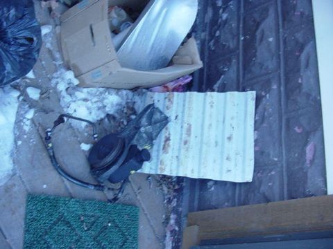1992 Ford Bronco - A power steering pump is shown on a cluttered floor, with a cardboard box and debris in the background.