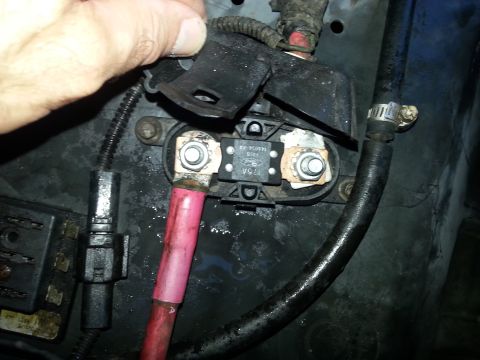 1992 Ford Bronco - A hand is shown adjusting a Ford alternator fuse, connected to thick red and black battery cables.