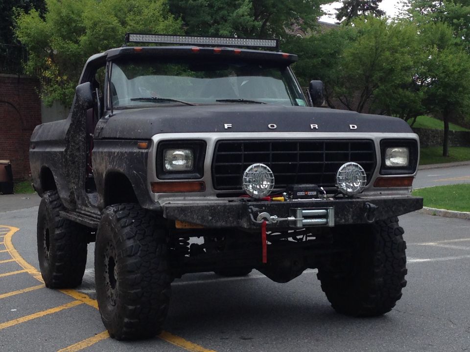 Black 1978 Ford Bronco with off-road modifications, including large tires, a winch, and a light bar