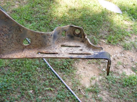 Close-up of a rusted metal bracket with several holes and slots