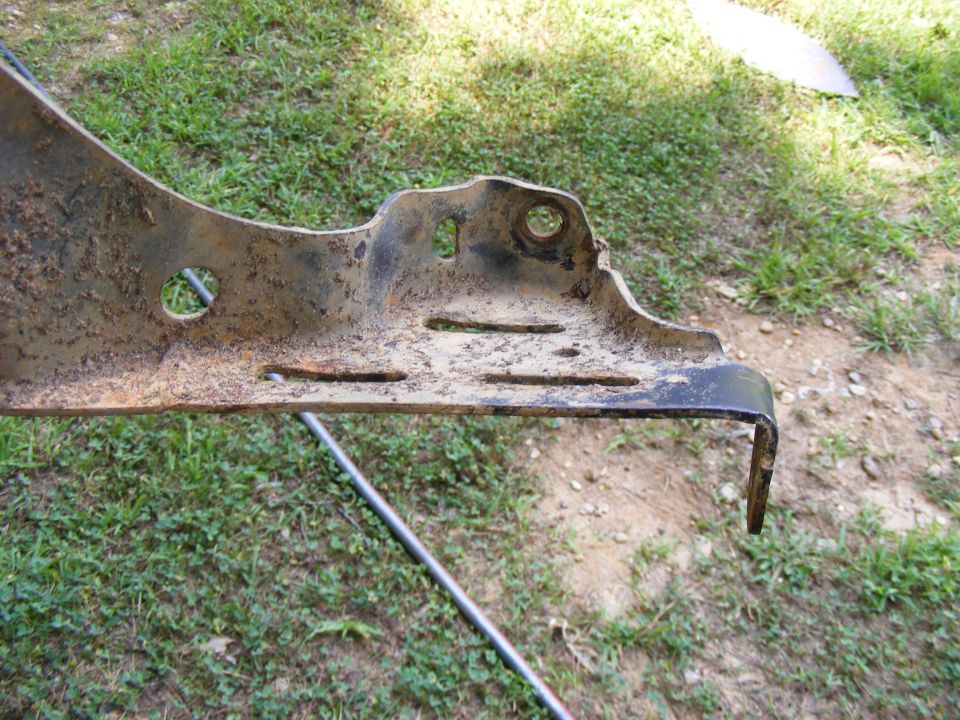 Close-up of a rusted metal bracket with several holes and slots