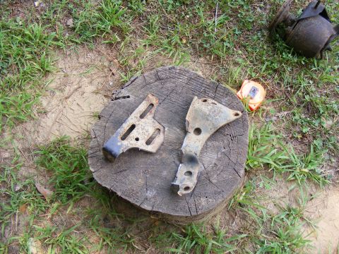 two old metal brackets sitting on a tree stump