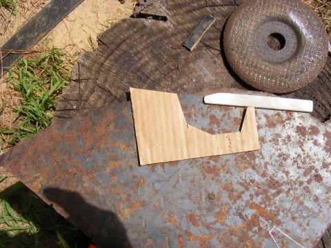 Cardboard template on rusty metal with grinding disc and wood stump