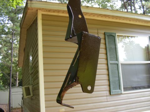 Painted metal bracket hanging in front of a tan sided building
