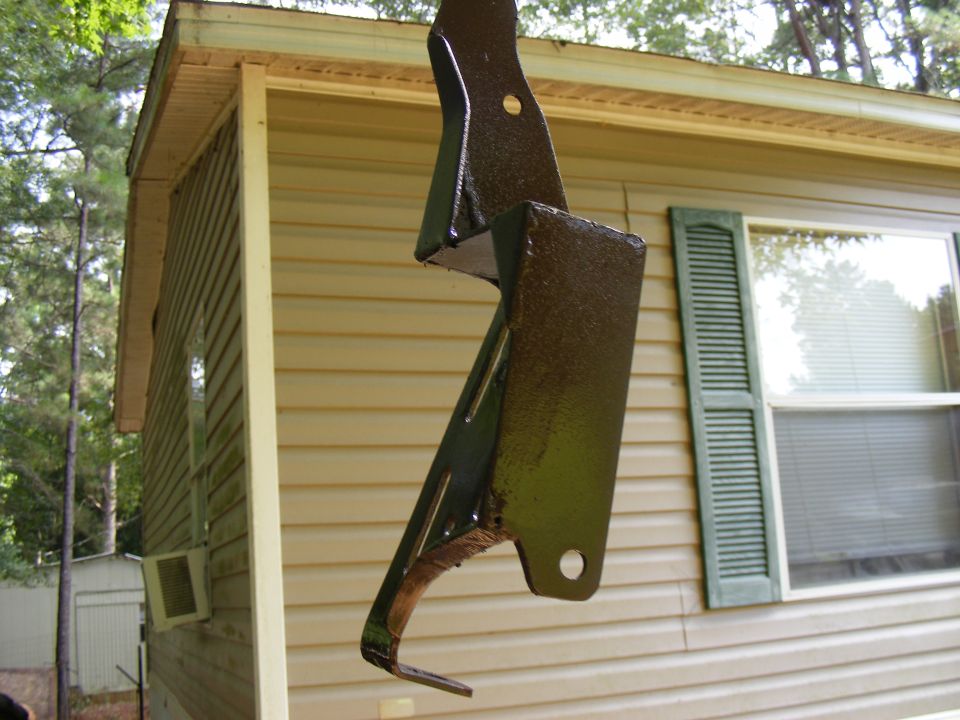 Painted metal bracket hanging in front of a tan sided building
