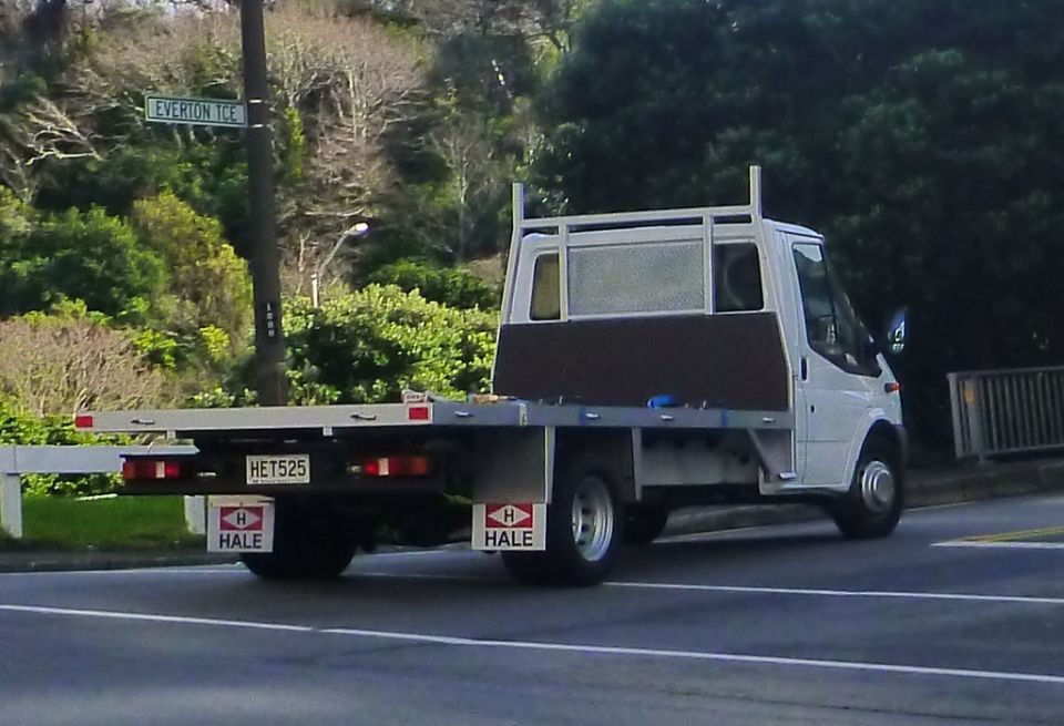 White flatbed truck with a license plate HET525 and HALE logos on the rear