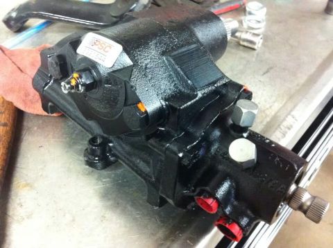 1988 Ford Bronco - A black power steering gearbox is shown up close with a PSC sticker and red capped fittings.
