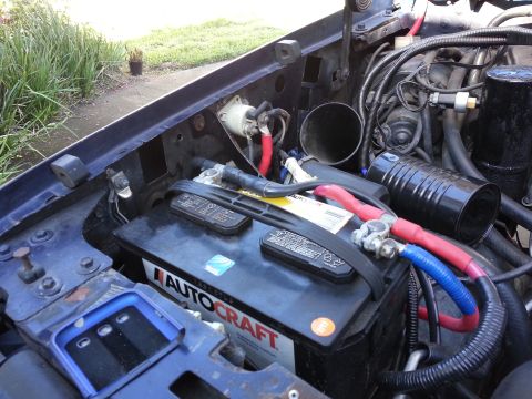 1994 Ford Bronco - Close-up view of a vehicle's engine bay, focusing on the battery and associated wiring.