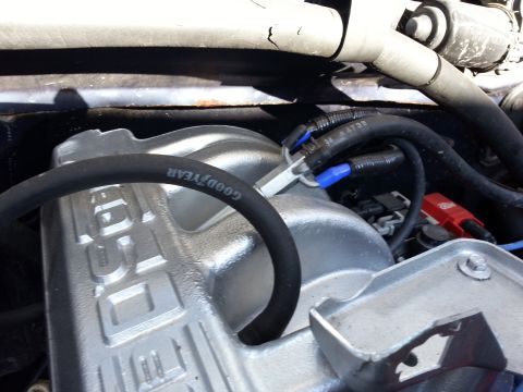 1994 Ford Bronco - Close-up of an engine's intake manifold and a Goodyear hose, with visible electrical connectors.