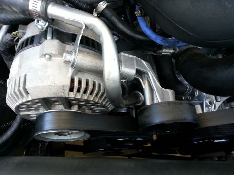 1994 Ford Bronco - Close-up view of the engine's alternator and belt system, showing pulleys and hoses.