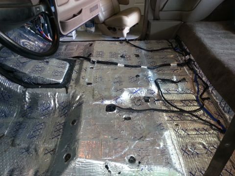 1994 Ford Bronco - The interior floor of a vehicle is covered in sound deadening material and exposed wiring.