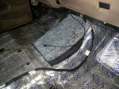 1994 Ford Bronco - Sound deadening material and wiring are visible on the floor of a vehicle's interior.
