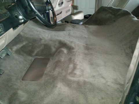 1994 Ford Bronco - Vehicle interior carpet, showing the floor and part of the dashboard and steering wheel.