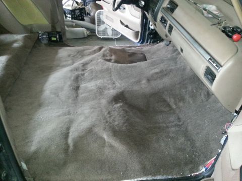 1994 Ford Bronco - Interior of a vehicle with the carpet removed, revealing the floor and dashboard components.