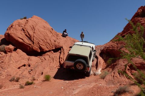 1995 Ford Bronco - An off-road SUV navigates a challenging rocky path under a clear blue sky.
