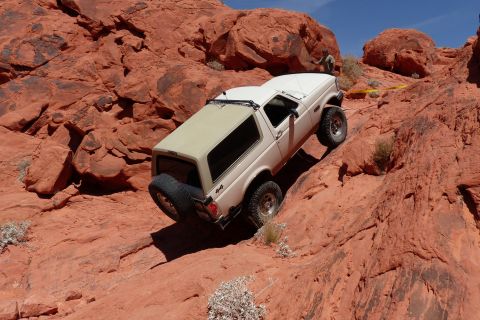 1995 Ford Bronco - White 1995 Ford Bronco navigating a challenging off-road trail in a desert landscape.