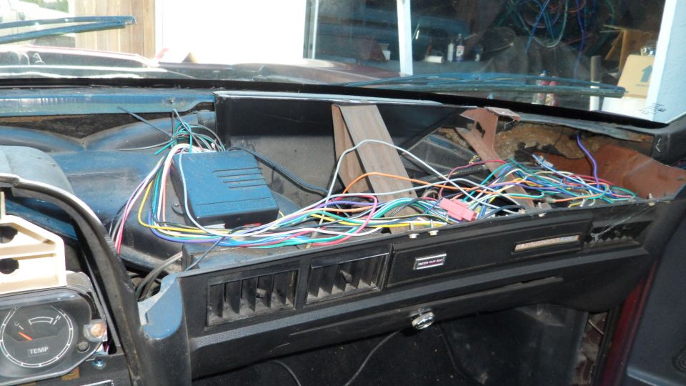 Car dashboard with exposed wiring and a blue electronic module