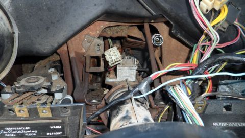 1972 Ford Ranchero - A close-up view of the complex wiring and rusted components within a vehicle's dashboard.