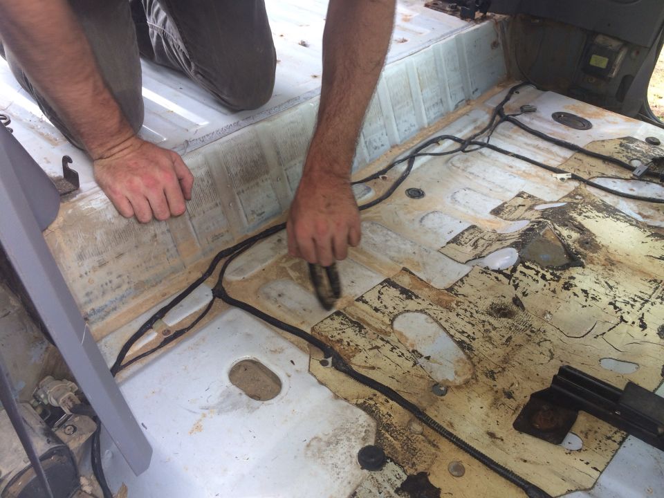 Interior floor of vehicle with wiring exposed, being cleaned