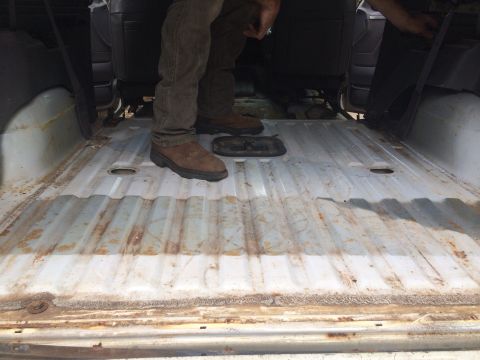 1994 Ford Bronco - Interior cargo area of a vehicle with a ribbed metal floor and visible rust.