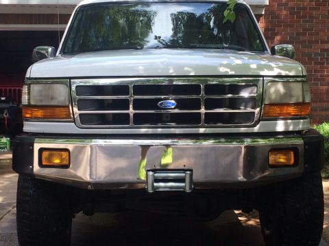 1994 Ford Bronco - Front view of a white Ford truck with a chrome bumper and grille, a winch.
