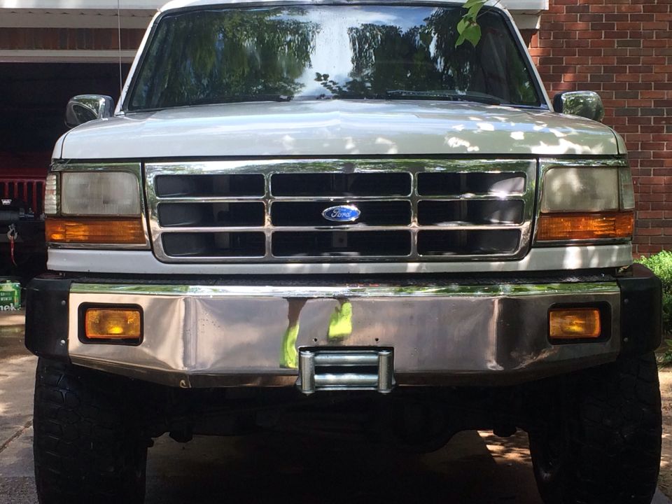 White Ford truck front view with chrome bumper and grille. Winch installed