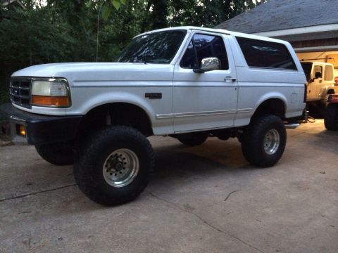 1994 Ford Bronco - This lifted 1994 Ford Bronco is parked on a concrete driveway next to a garage.