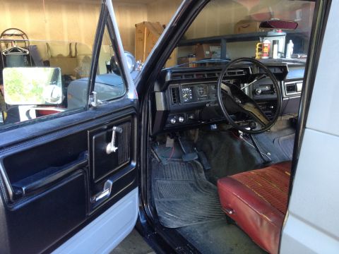 1982 Ford Bronco - The interior of a classic Ford Bronco, viewed from the open driver's side door.