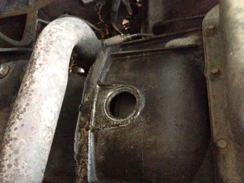 1996 Ford Bronco - Close-up view of an exhaust pipe and a greasy engine component.