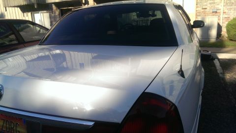 2000 Mercury Grand Marquis - Rear view of a white 2000 Mercury Grand Marquis, with another vehicle partially visible to the left.