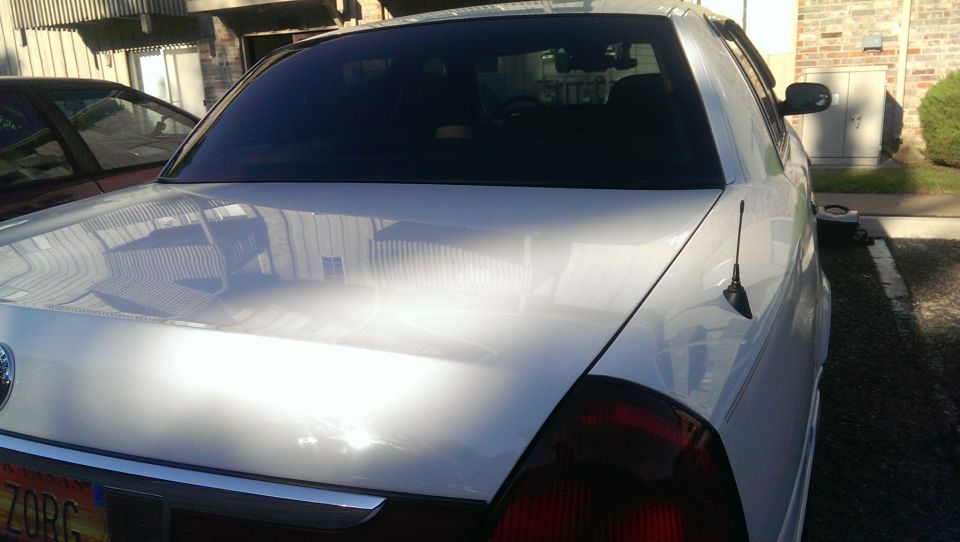 White 2000 Mercury Grand Marquis rear view. Another car is parked to the left