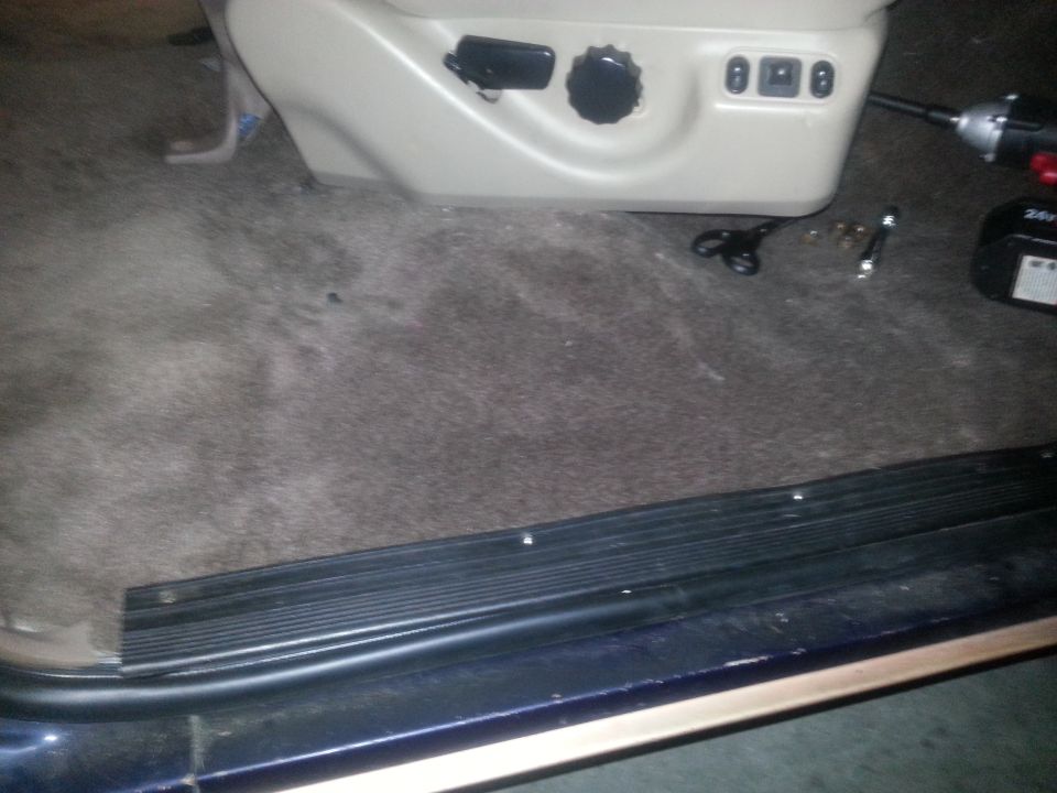 Carpeted floor and beige seat controls with black knobs and buttons. Scissors and tools are on the floor