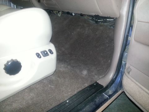 1994 Ford Bronco - Interior view of a car's floor and seat controls, showing the carpet and door trim.