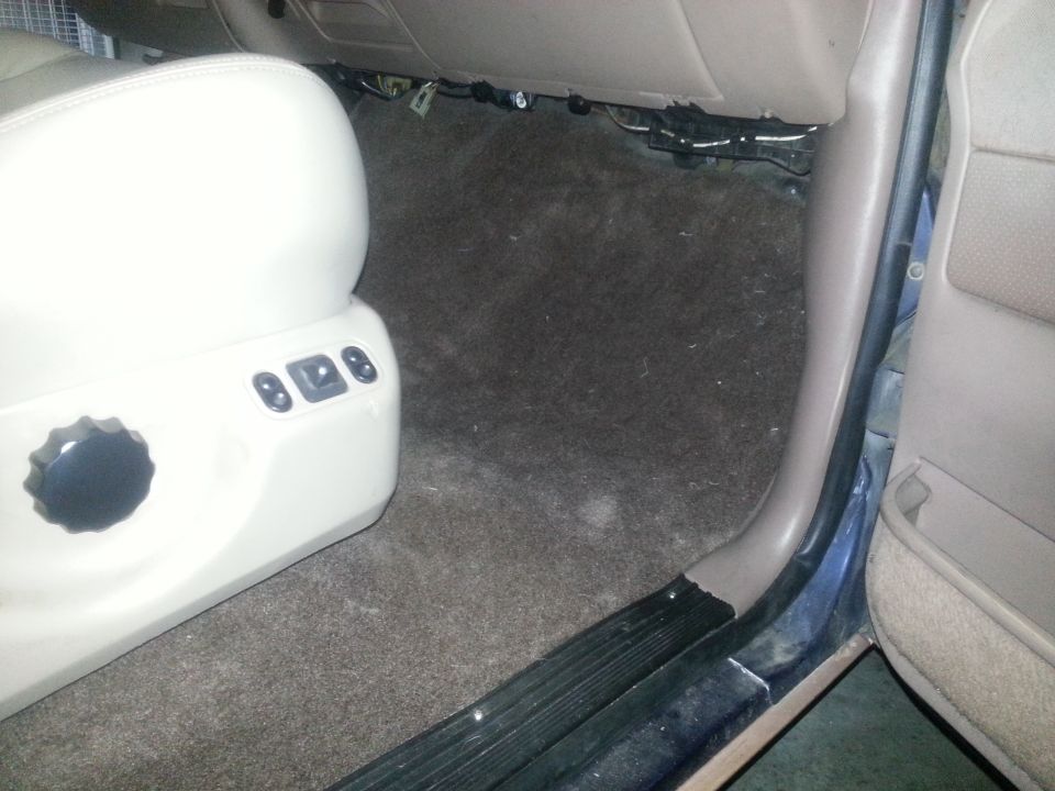 Carpeted floor and beige seat controls inside a vehicle