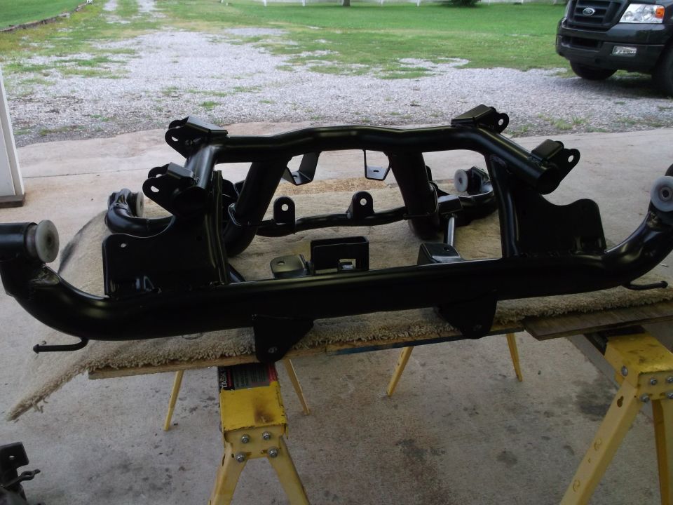 Black painted car suspension subframe assembly on sawhorses