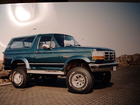 1996 Ford Bronco - Teal green 1996 Ford Bronco parked outdoors, showing its distinctive body style and off-road tires.