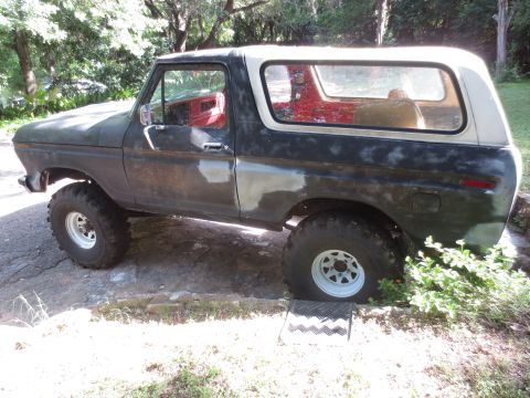 1978 Ford Bronco - A 1978 Ford Bronco sits outdoors, showing signs of preparation for paint with visible primer patches and large off-road tires.