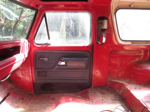 1978 Ford Bronco - Interior view of a red vehicle, showing the door panel and floor, possibly undergoing restoration.